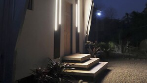 Una casa moderna con un diseño arquitectónico único, que presenta un techo inclinado y una entrada bien iluminada.