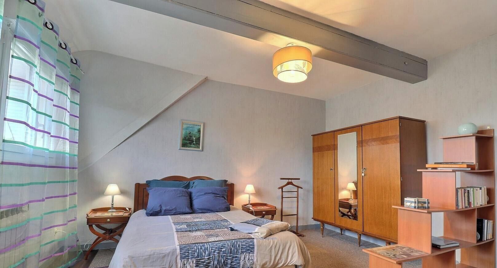 Un dormitorio con cama, mesitas de noche, un armario y una estantería.