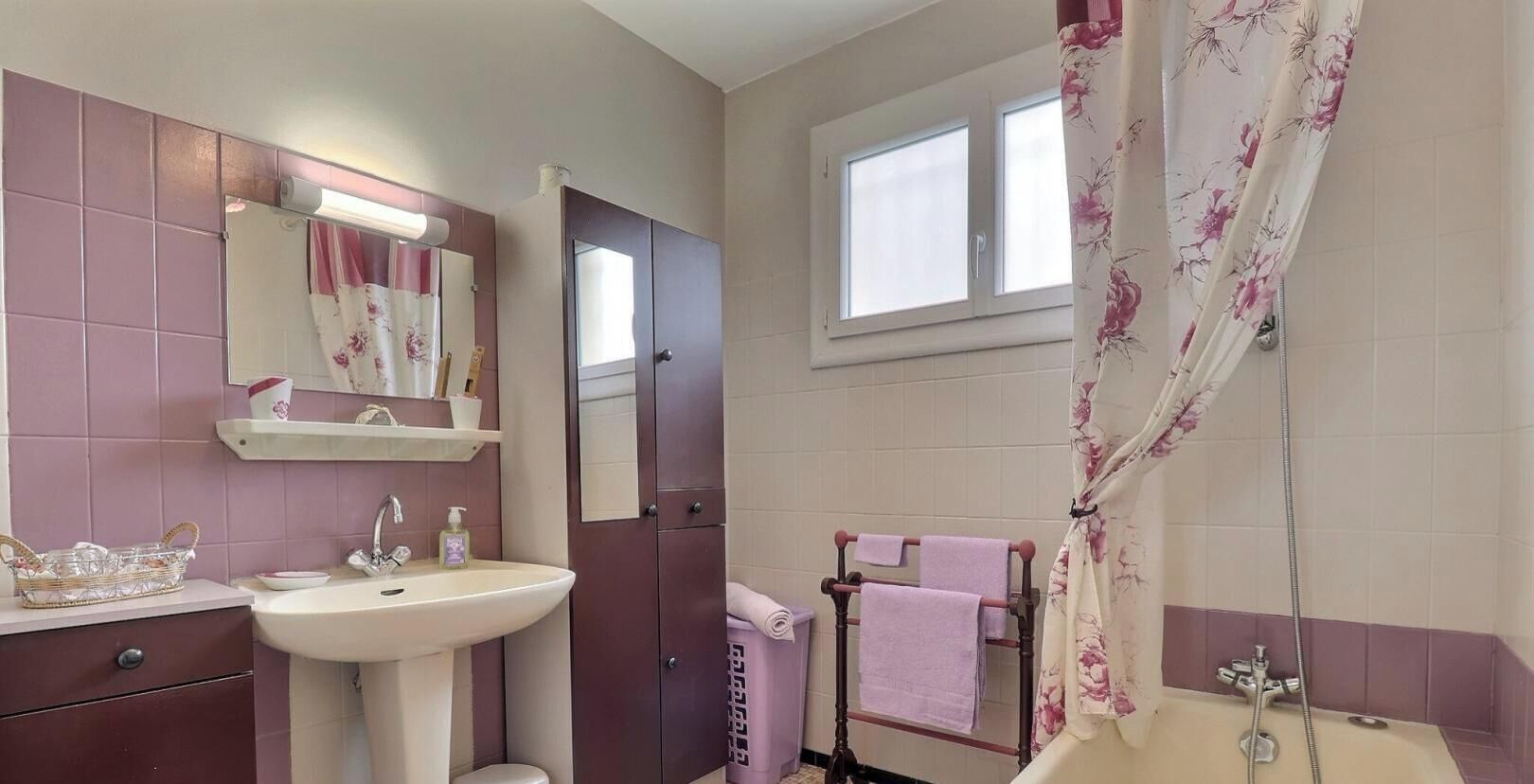 A bathroom with a sink, mirror, vanity, toilet, shower, and a window.