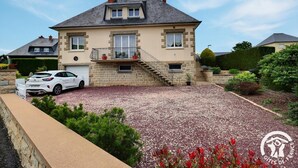 A two-story house with a stone facade, a balcony, and a gravel driveway.