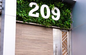 Ein Gebäude mit der Hausnummer 209, einem Metallgitter und einer grünen, mit Pflanzen bewachsenen Wand.