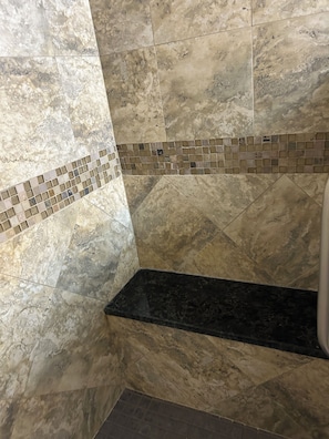 A bathroom with marble tiles, a black countertop, and a mosaic tile border. - Completely revamped Eastern Shore home (Onley)