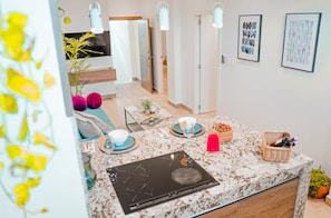 A modern kitchen with a granite countertop, a black induction cooktop, and a dining area with a table set for two.