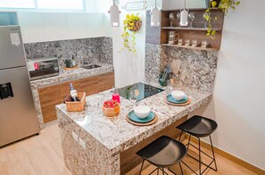 A modern kitchen with granite countertops, a built-in oven, a sink, and a dining area with stools.