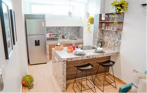 A modern kitchen with granite countertops, a built-in refrigerator, and bar stools.