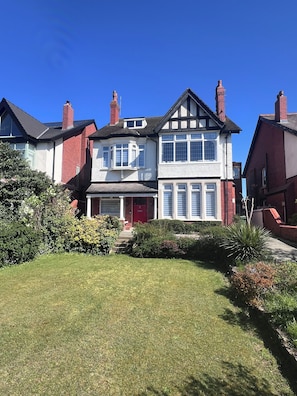A two-story house with a red door, white and red brick exterior, and a well-maintained lawn. - 253
Stylish Coastal Retreat ground floor  1507sqf (Lytham St Annes)