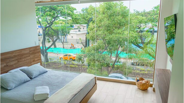 Ein Schlafzimmer mit Bett, Fenster und Blick ins Freie.