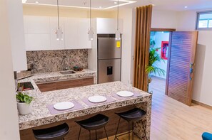 Une cuisine moderne dotée de plans de travail en granit, d’appareils électroménagers en acier inoxydable et d’un coin bar avec des tabourets.