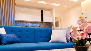 A modern living room with a blue sofa, a marble coffee table, and a kitchen area in the background. - 07 Luxury Apartment Los Angeles style, brand new (Guayaquil)