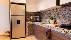 A kitchen with a stainless steel refrigerator, a microwave, a sink, and a wooden cabinet. - 07 Luxury Apartment Los Angeles style, brand new (Guayaquil)
