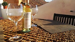 A table with a bottle of wine and two glasses on a woven tablecloth. - Nautilus - Cozy Apartment with Terrace in the City Center (Cagliari)
