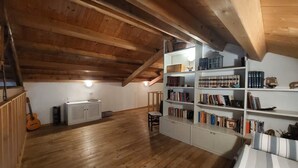 A room with wooden beams, a bookshelf, a radiator, and a guitar. - Nautilus - Cozy Apartment with Terrace in the City Center (Cagliari)