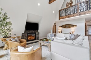 Un salon moderne avec une cheminée, des canapés en cuir et un plafond décoratif.