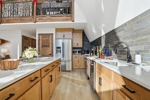Une cuisine moderne avec des meubles en bois, des appareils électroménagers en acier inoxydable et un dosseret de carrelage noir.