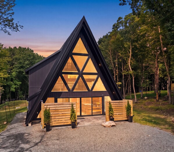 Un bâtiment moderne de forme triangulaire, doté de grandes fenêtres et d’une allée gravillonnée.