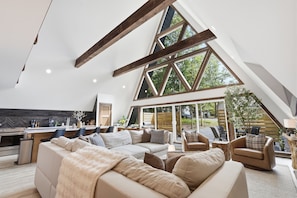 Ein geräumiges Loft mit hoher Decke, freiliegenden Holzbalken, einem großen Essbereich und Blick ins Freie.