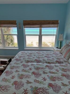 Ein Schlafzimmer mit Bett, Blick auf den Strand und Fenster mit Meerblick.
