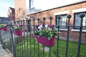 Ein Backsteinhaus mit einem Metallzaun und Blumenkästen.