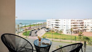 Ein Balkon mit Meerblick, ein Parkplatz und ein mehrstöckiges Gebäude.