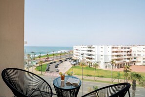 Ein Balkon mit Meerblick, ein Parkplatz und ein mehrstöckiges Gebäude.