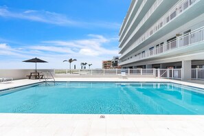 A swimming pool with a no diving sign, a picnic table, and a view of a multi-story building. - Sunset Chateau 502 (Treasure Island)
