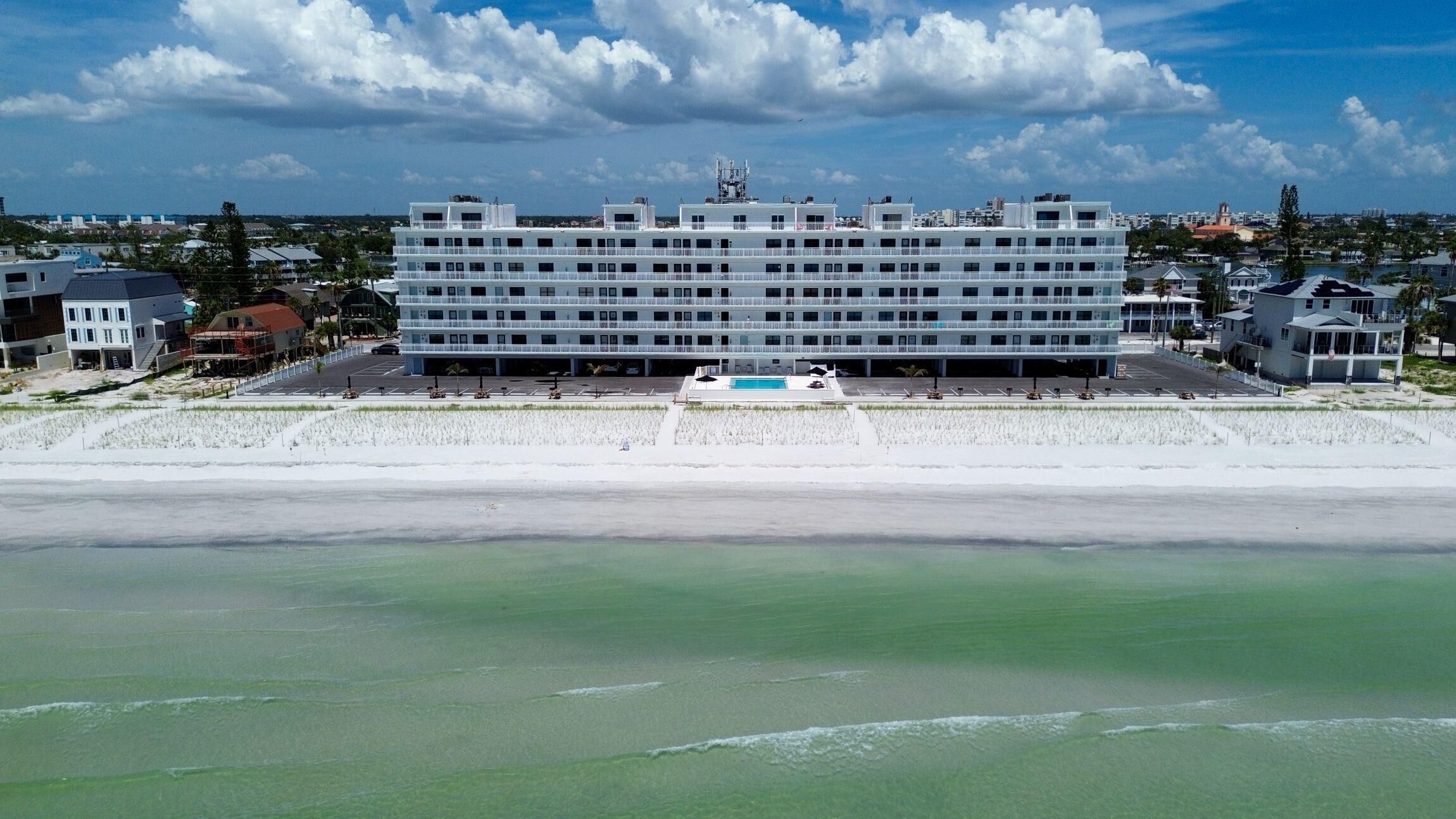 Ein mehrstöckiges Hotel mit Swimmingpool und Blick auf den Strand.
