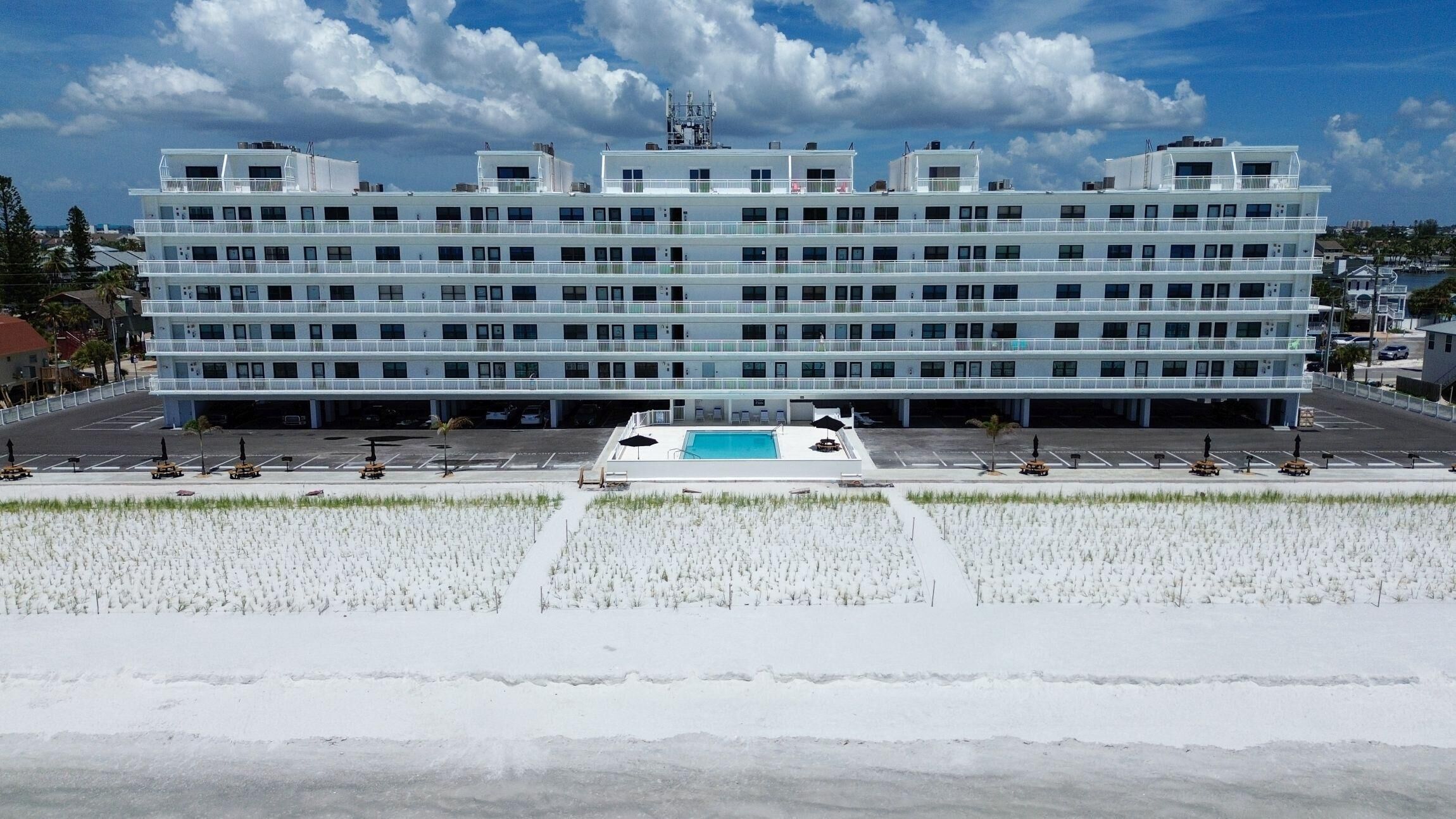 Ein mehrstöckiges Hotel mit Schwimmbad und Parkplatz.