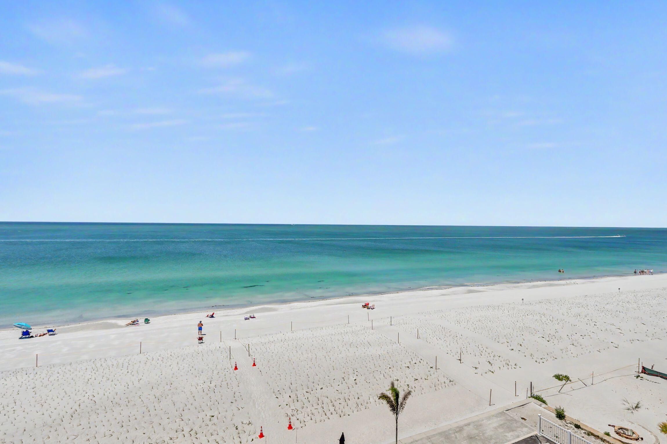 A beach with a clear sky, calm sea, and a sandy shore.