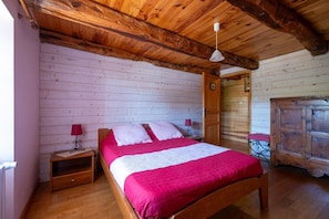 A wooden-framed room with a bed, a nightstand, a red lamp, and a wooden cabinet. - At the foot of the Aubrac - SALCES (LES) (SALCES (LES))