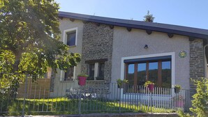 A stone building with a balcony, potted plants, and a metal fence. - GÎTE GABRIELLE - BAGNOLS-LES-BAINS (BAGNOLS-LES-BAINS)