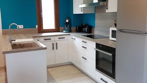 A modern kitchen with white cabinetry, a built-in oven, a microwave, and a coffee maker. - GÎTE GABRIELLE - BAGNOLS-LES-BAINS (BAGNOLS-LES-BAINS)