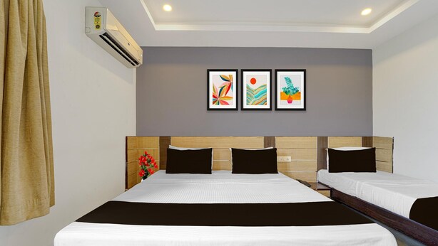 Habitación de hotel con dos camas, cabecera con panel de madera, aire acondicionado de pared y tres obras de arte enmarcadas.