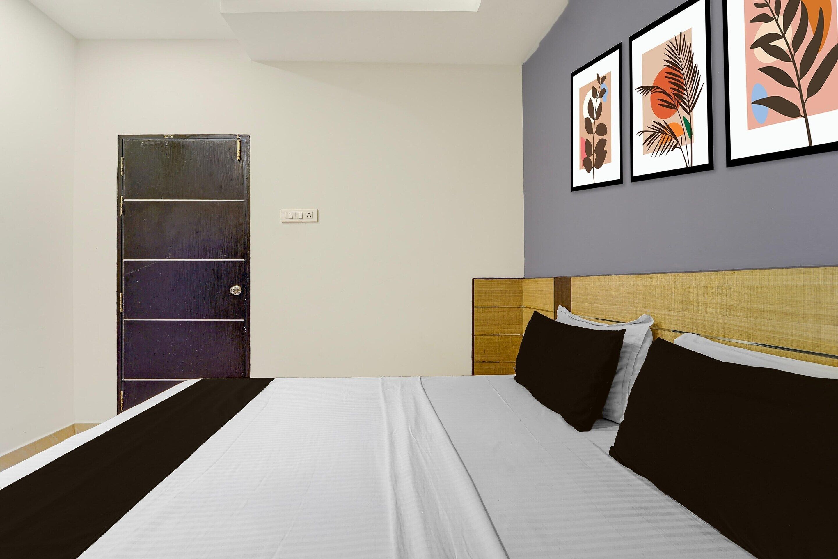 Un dormitorio con cama, cabecera, una puerta y obras de arte en la pared.