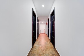 A long, narrow hallway with doors on both sides, a tiled floor, and a ceiling light.