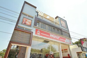 A multi-story building with a visible storefront for a service franchise, including a sign for tyres and service. - Classic Sathya Inn (Madurai)