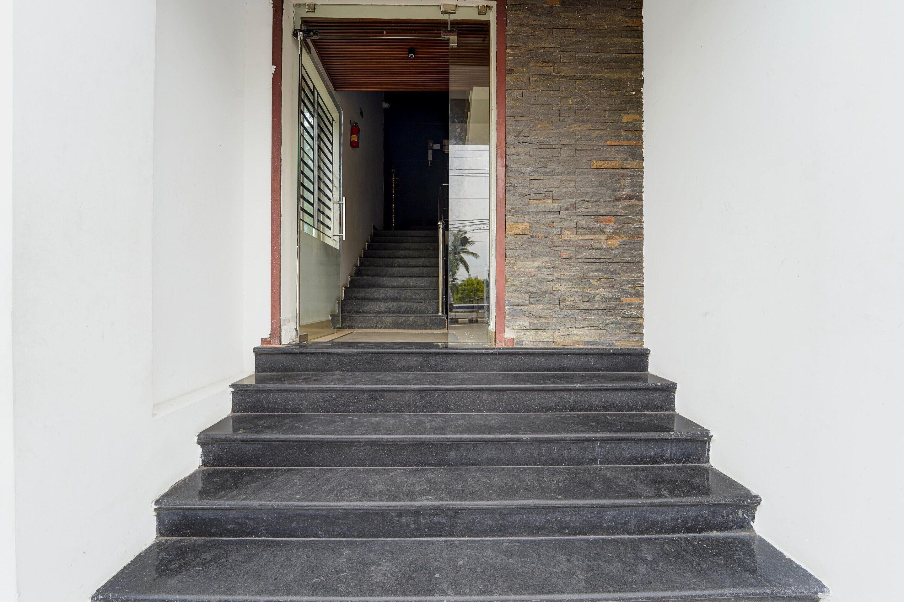 A staircase leading to a room with a stone wall and a fire extinguisher on the wall.