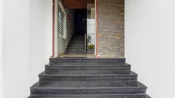 A staircase leading to a room with a stone wall and a fire extinguisher on the wall.