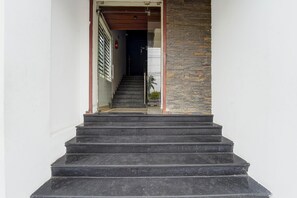 Una escalera que lleva a una habitación con una pared de piedra y un extintor en la pared.