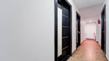 Un pasillo con una puerta negra, una pared blanca y un suelo de baldosas.