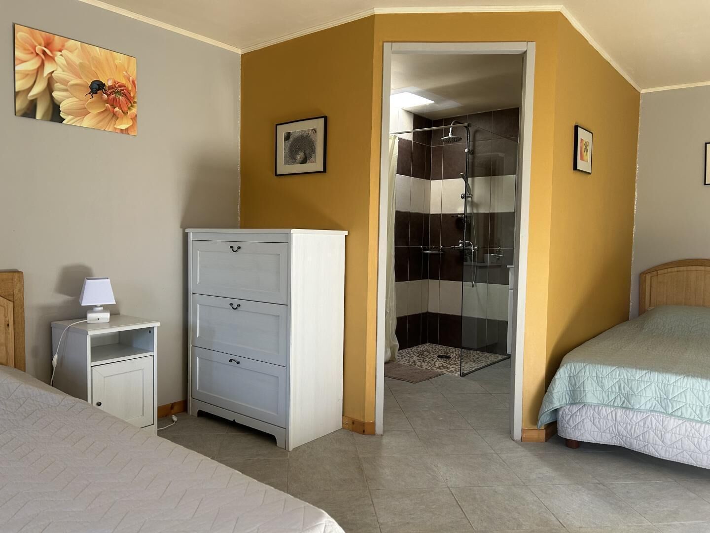 Een slaapkamer met een bed, een nachtkastje met een lamp, een dressoir en een douche.