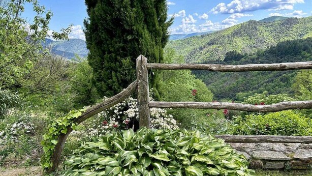 A rustic wooden fence, lush greenery, and a mountainous backdrop. - Gîte de Poussiels - SAINT ANDEOL DE CLERGUEMORT (SAINT ANDEOL DE CLERGUEMORT)