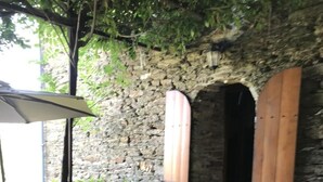 Eine Terrasse mit Tisch und Stühlen, einer Steinmauer und Holztüren.