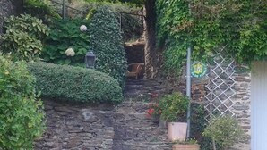 Eine Steintreppe mit Blumentöpfen und Blumen, einer Laterne und einem Metallzaun.
