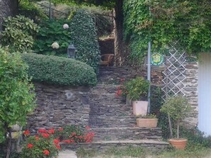Una escalera de piedra con macetas y flores, un farol y una valla de metal.