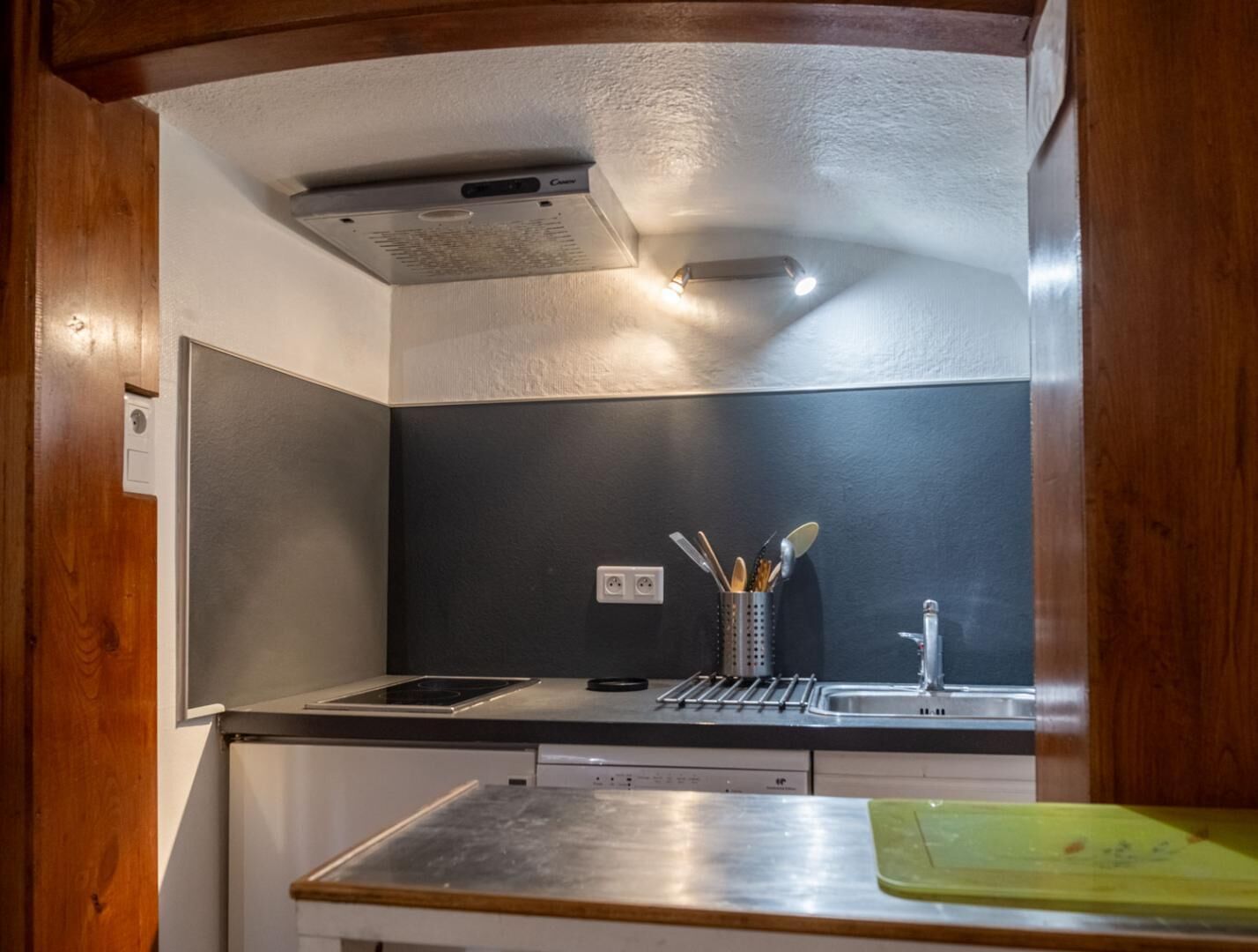 Une cuisine compacte équipée d’une cuisinière intégrée, d’un évier et d’un porte-ustensiles.