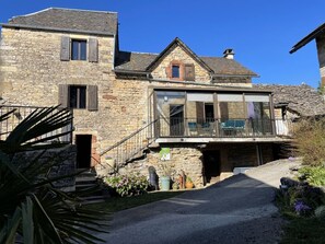 Ein Gebäude aus Stein mit Balkon, Treppe und Auffahrt.