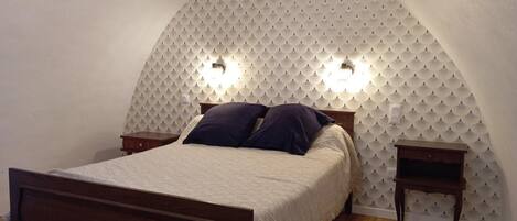 A bedroom with a bed, two bedside tables, and a unique ceiling design.