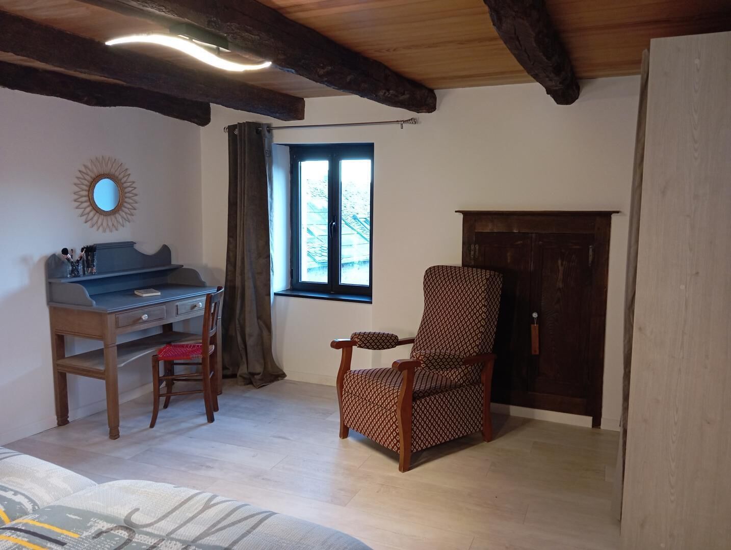 A room with a desk, chair, window, and a wardrobe.