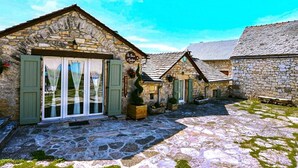 A stone building with a sign reading 'La Maison des Vignerons,' a stone-paved courtyard, and a small garden area. - Le Four d'Odilon 6 people in Montignac (MALENE (LA))