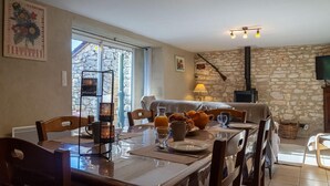 A dining area with a stone wall, a fireplace, and a television. - Le Four d'Odilon 6 people in Montignac (MALENE (LA))